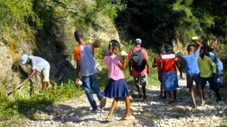 Haiti IMPACT Club in the Miragoane, Haiti, community fixing a dirt road so that motorcycles can travel safely on it. 