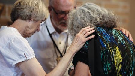 Volunteers pray during a worship service at Synod 2024