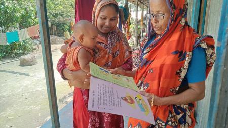 Saleha, a community health volunteer, provides health training to a young mother.