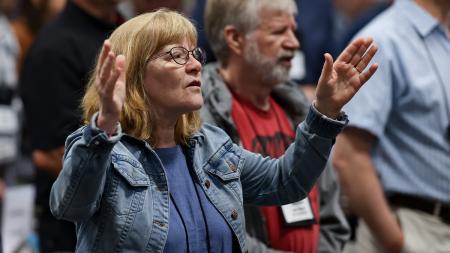 Synod delegates sing “To God Be The Glory” at the end of a plenary session.