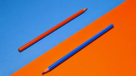 a red pencil on a blue background and a blue pencil on a red background