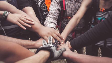 hands meeting in the center of a circle of community activists