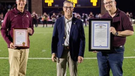 Michigan senator Mark Huizenga (center) presented an official proclamation and legislative tribute to Calvin University president Greg Elzinga and Calvin Theological Seminary president Jul Medenblik during a homecoming football game.