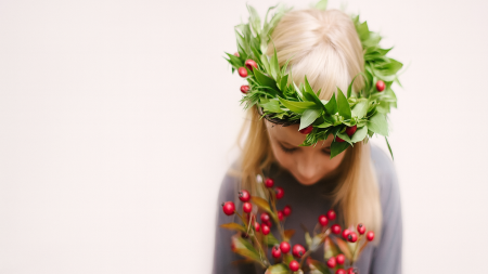 A woman is looking down with a crown of greenery on her head