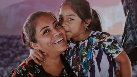 A young daughter kisses her mom on the cheek