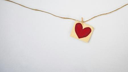A red heart hanging on a wall on a string
