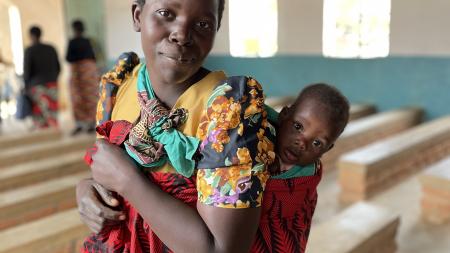 This mother, photographed with her baby in their church in Malawi, is working with her community to build stronger families