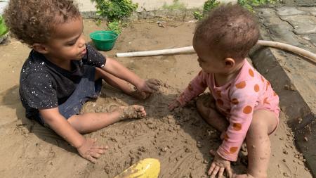 Two toddlers play in the sand
