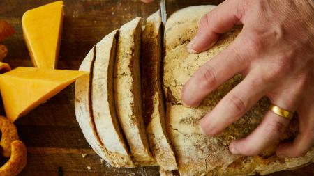 A person cutting a loaf of bread