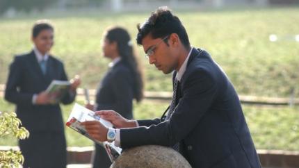 a young man in business clothes reads outside