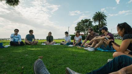 group of youth sitting on grass at a park