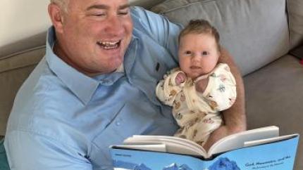 man holding baby reading a book