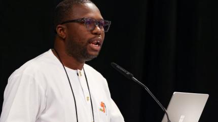 Moses Jawara speaks into a microphone