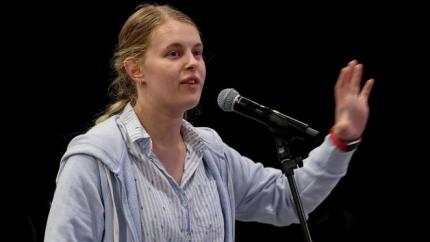 Hannah denBak speaks into a microphone