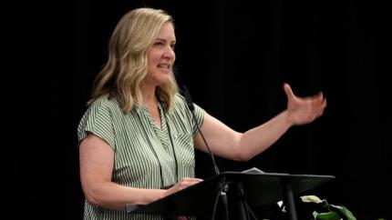Susan LaClear speaks from a podium into a microphone