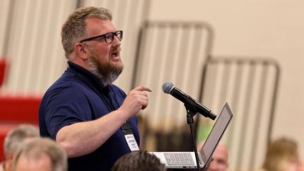 man speaking into a microphone at Synod