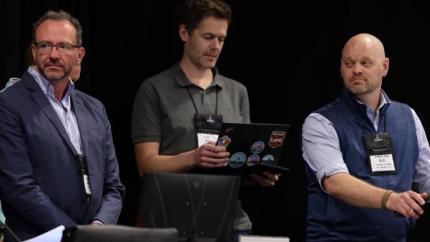 Three men speaking at a podium