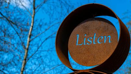 A metal sculpture with the word 'Listen' etched on it