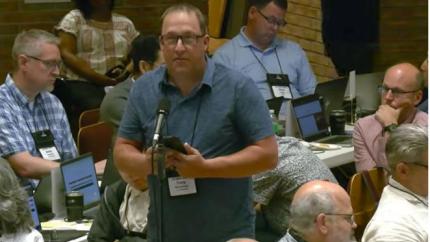 Synod 2026 delegate speaks into a microphone