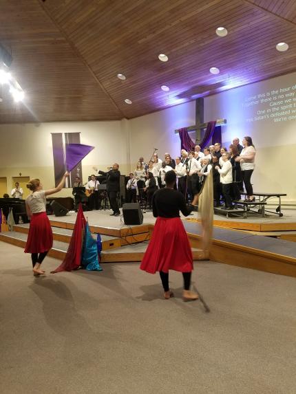 The mass choir sings as young women wave banners at the start of the service.