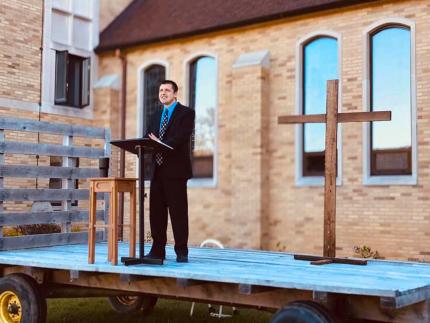 Pastor Lloyd Hemstreet preaches from a hay wagon.