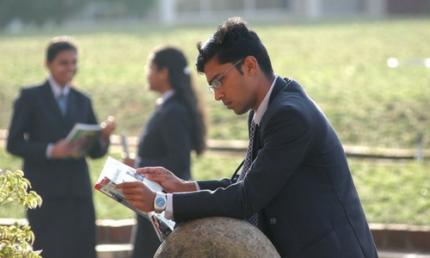 a young man in business clothes reads outside