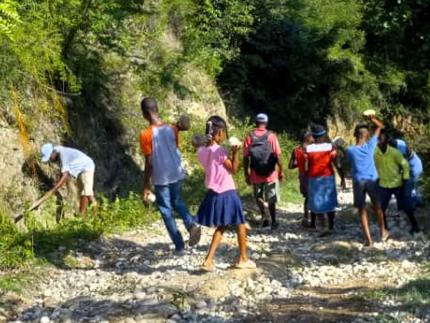 Haiti IMPACT Club in the Miragoane, Haiti, community fixing a dirt road so that motorcycles can travel safely on it. 