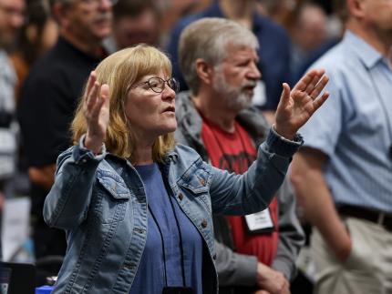 Synod delegates sing “To God Be The Glory” at the end of a plenary session.
