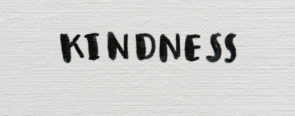 black calligraphy on white paper spelling the word kindness