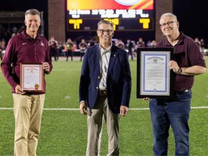 Michigan senator Mark Huizenga (center) presented an official proclamation and legislative tribute to Calvin University president Greg Elzinga and Calvin Theological Seminary president Jul Medenblik during a homecoming football game.