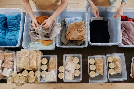 An overhead shot of a table that has containers with cans of soup, crackers, and clothing donations