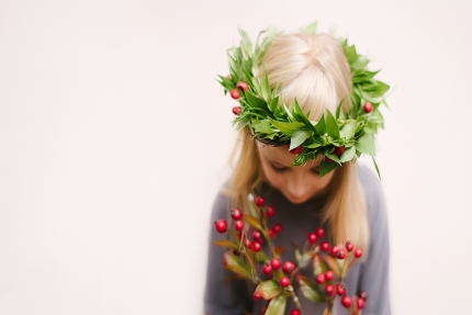 A woman is looking down with a crown of greenery on her head
