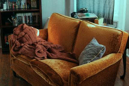 A cozy couch with a blanket and a pillow