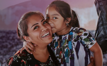 A young daughter kisses her mom on the cheek