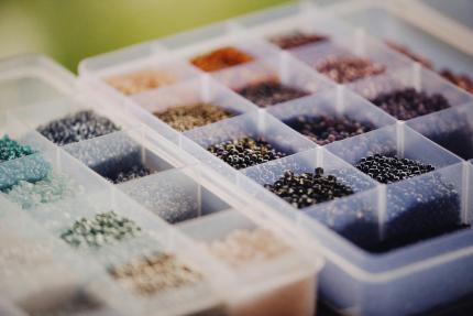 A container divided into compartments holds small beads