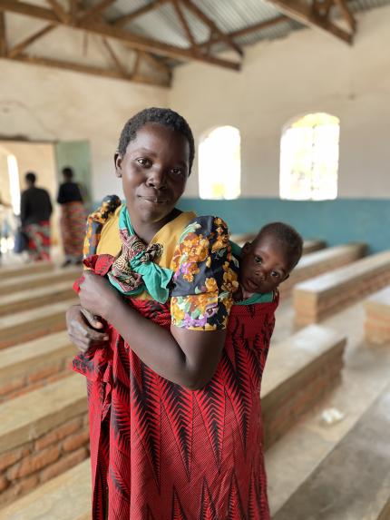 This mother, photographed with her baby in their church in Malawi, is working with her community to build stronger families