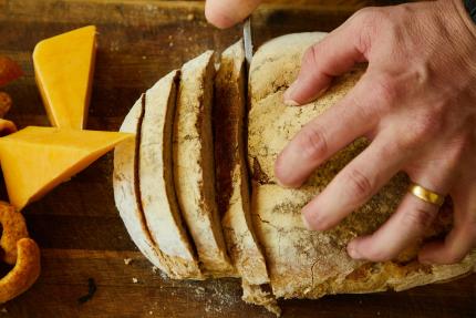 A person cutting a loaf of bread