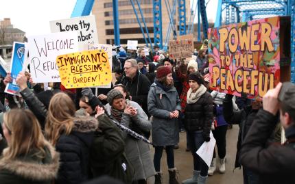 Participants in “Bridges Not Walls” event hold signs.