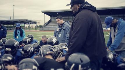 Pastor Clarence Presley prays for football team after a recent championship game.