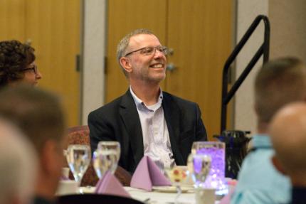 Professor Michael Williams smiles during a synod banquet held in his honor