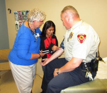 Ilzhe Hernandez takes the blood pressure of William Corner as Joanne Rozema looks on.