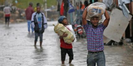People carry their belongings as they wade across a flooded street while Hurricane Matthew passes through Port-au-Prince, Haiti.