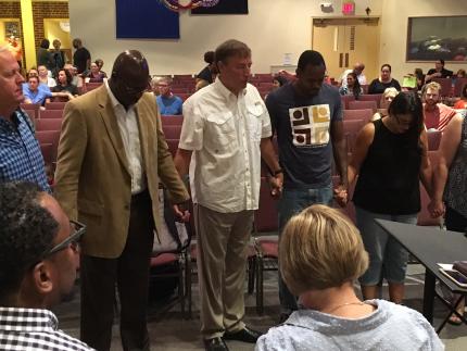 Colin P. Watson Sr. (left in tan jacket) prays with others during a service for Charlottesville, Virginia.