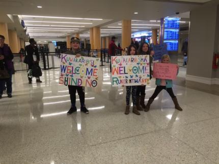 Members of Oakland CRC wave welcome signs at the airport in Grand Rapids, Mich.