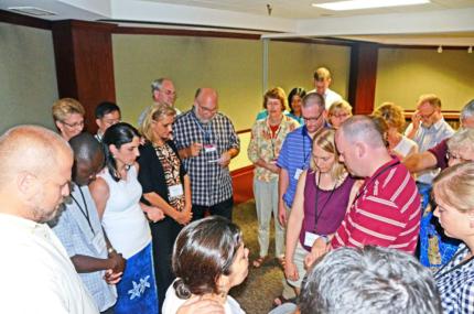Joel Hogan (center) helps lead prayer at the commissioning service.