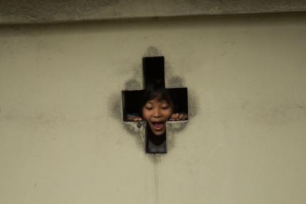 A young person peers through the image of a cross in a church in Aizawl.