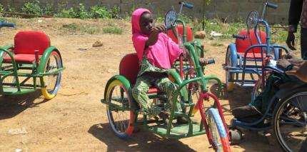 Young girl rides in a wheelchair provided by the Beautiful Gate.