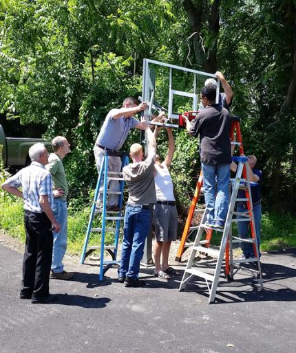 Immanuel CRC members building the stand and backboard for their parking lot basketball court.