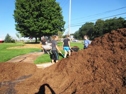 Volunteers move mulch in front of CRC office.