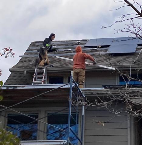 Two people installing solar panels on a roof